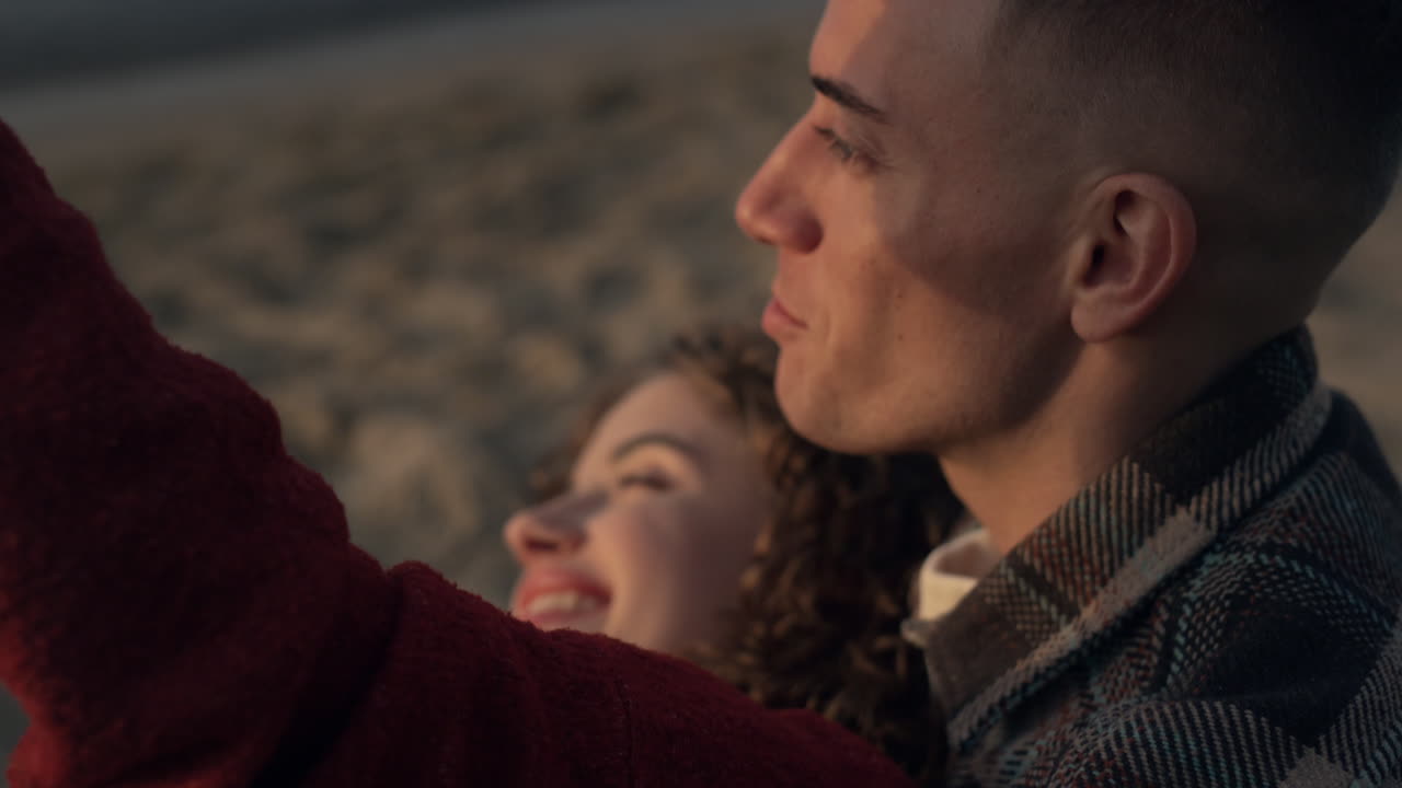 Pareja haciéndose una selfie en la playa al amanecer. Enamorados coqueteando entre sí.