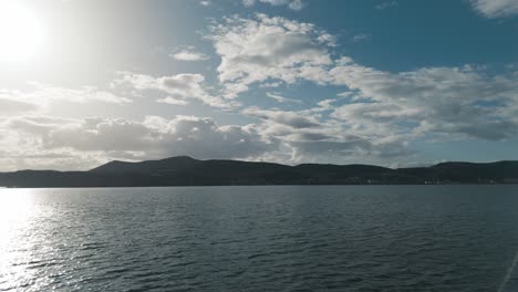 a rotating silhouette drone shot a village mountain, warm weather, flying above a dreamy lake, 4k video, european spring nature, beautiful landscape, white scenic clouds