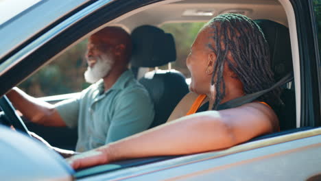 senior couple enjoying day trip out driving and sightseeing in car together
