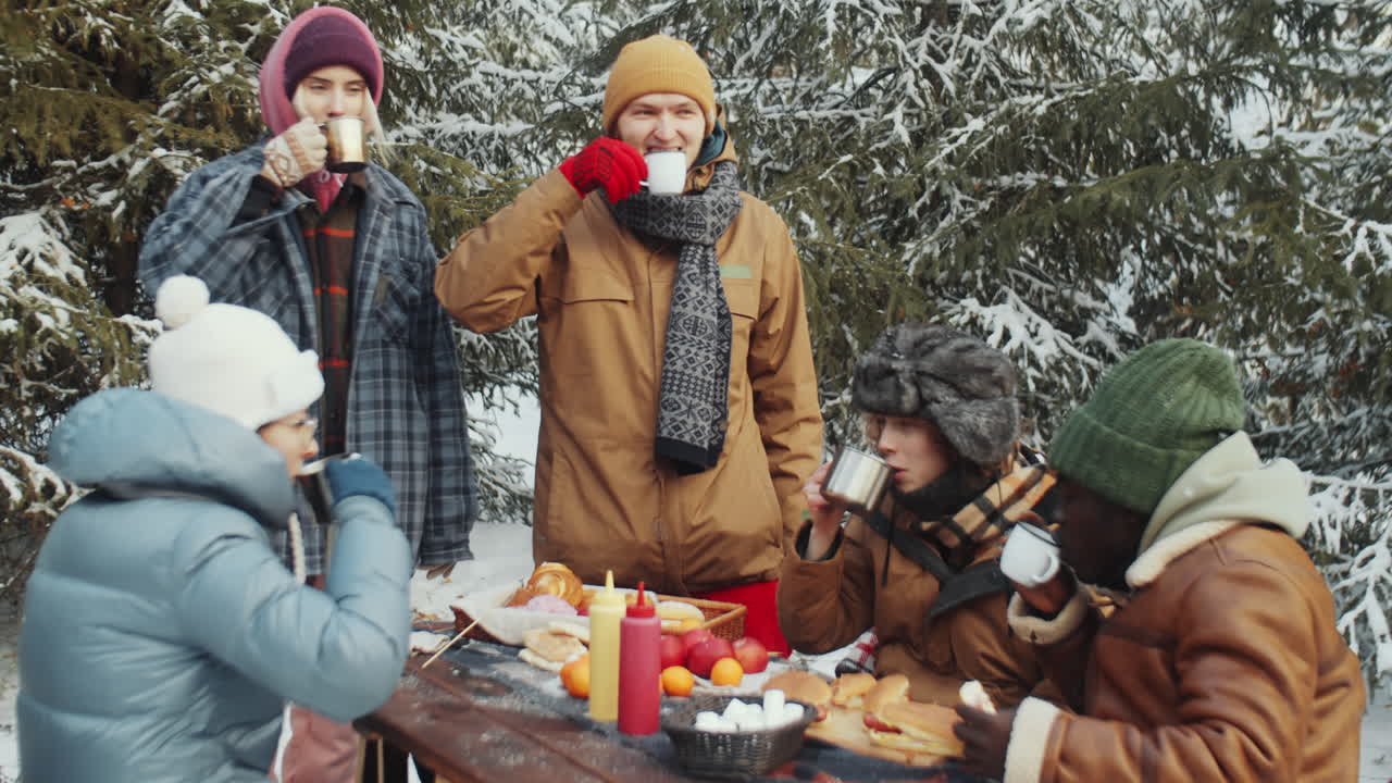 친구 들 이 겨울 숲 에 있는 캠핑장 에서 술 을 마시고 토스 하고 있다