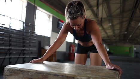 female athlete in a gym leaning on a piece of equipment while catching her breath