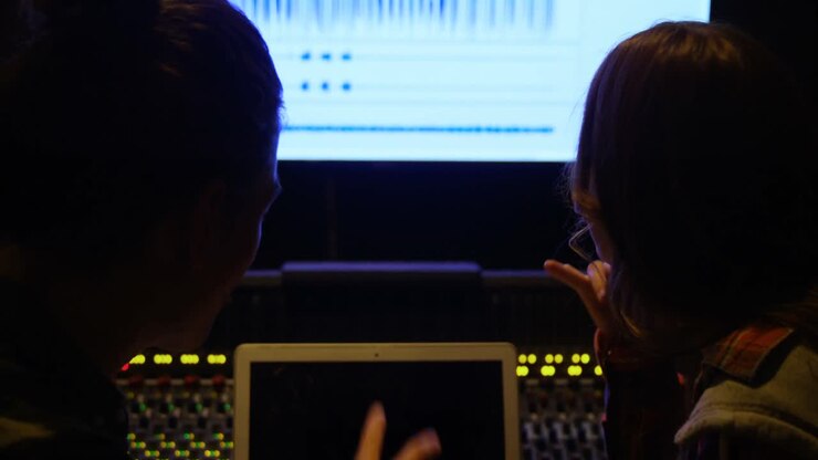 Audio engineers using laptop while mixing sound
