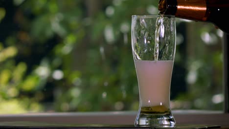 verter cerveza en un vaso de tulipán con plantas en el fondo en cámara lenta-1