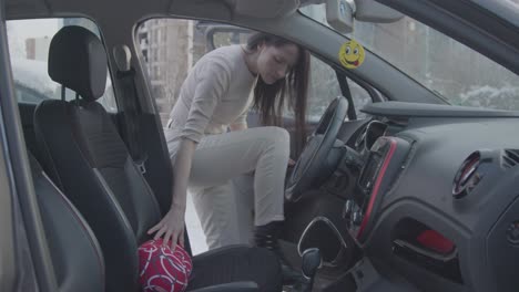 a european woman slipping the lumber support pillow in driver's seat to have a comfortable sitting position to avoid lower back pain