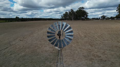 tomada aérea hacia atrás de un molino de viento giratorio en un campo de granja durante un día nublado , región del río margaret