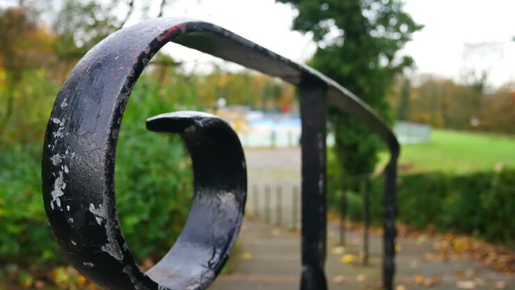 Slow panning shot across wrought iron curved hand rail leading down to park play area