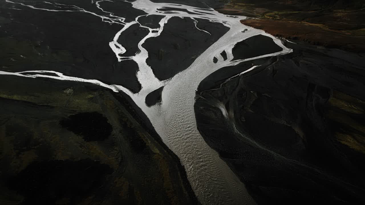 Aerial tilt up thor valley, flying over glacial river flowing through black volcanic mountains, thorsm&ouml;rk dramatic moody landscape Iceland