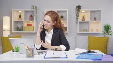una trabajadora de oficina en casa hablando felizmente por teléfono.