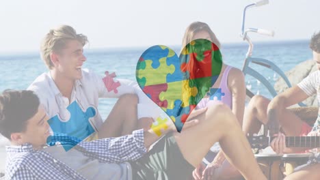 Animation-of-colourful-puzzle-pieces-heart-over-happy-friends-at-summer-beach-party