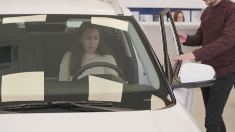 beautiful young couple at car showroom choosing a new car to buy.