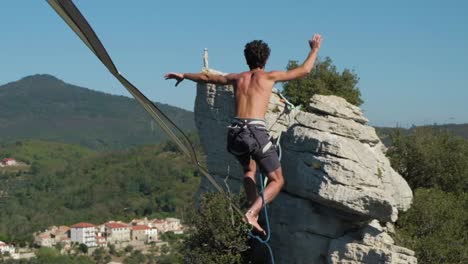 toma de cardán de hombres en un slackline en la cima de una montaña