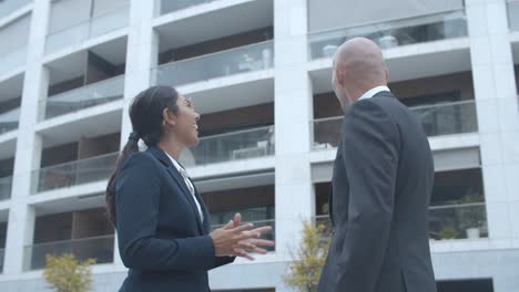 happy business colleagues meeting at office building, giving high five and discussing successful project or contract