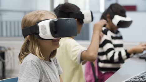 niños que usan auriculares de realidad virtual durante la lección de informática