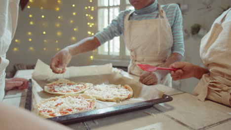 kids adding cheese to pizza before baking on cooking masterclass