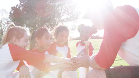 girls baseball team and male coach having team talk