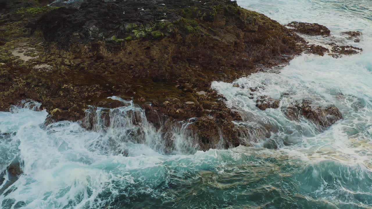 Ripresa con drone di onde che si infrangono su una roccia in spiaggia