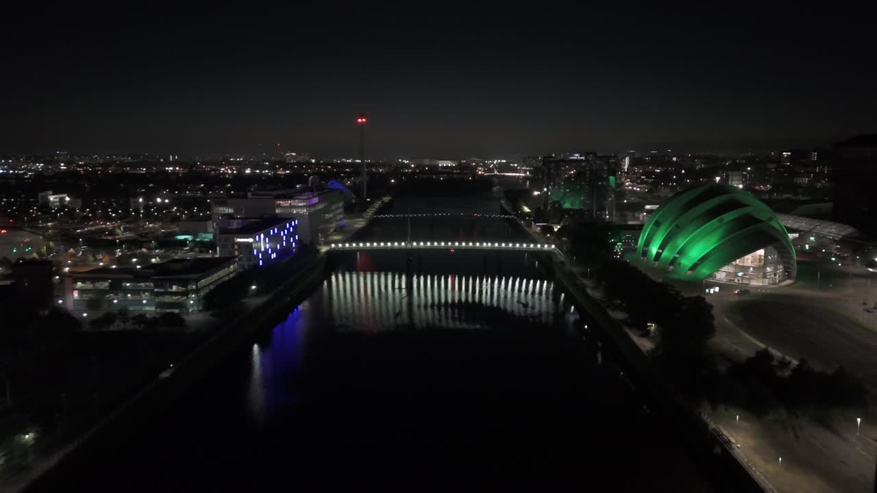 Conference arena, river water reflections, illuminated buildings
