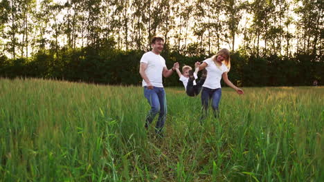 happy family: father, mother and son, running in the field dressed in white t-shirts