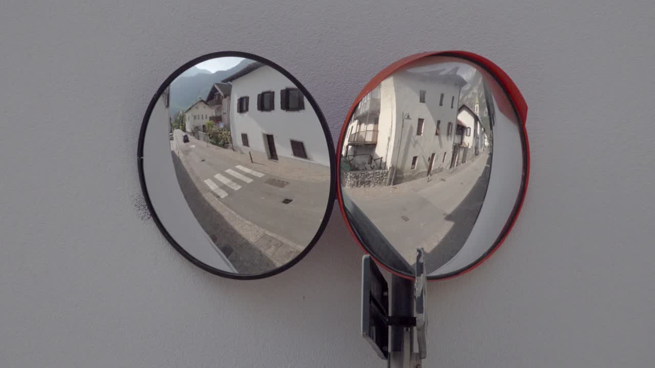 The reflection of a car in two mirrors driving past in Kurtinig - Cortina, South Tyrol, Italy