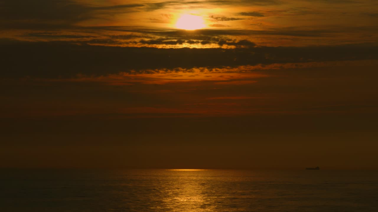 Beautiful View Over Ocean at Sunset with Reflection Ripples on Sea with Dramatic Cloudscape and Dark Orange Colors 4K