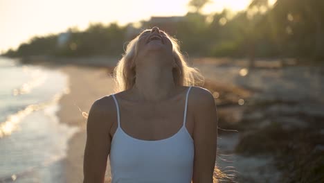 Cámara-Lenta-De-Mujer-Madura-Retroiluminada-En-La-Playa-Balanceando-Su-Cabello-Y-Jugando-Con-él-Con-Las-Manos-Y-Luego-Sonriendo-A-La-Cámara