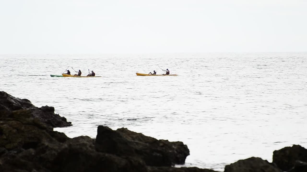 Flere havkajakroere padler langs den lyse horisont på det sydlige Stillehav nær Quepos, Costa Rica