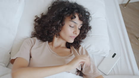 woman waking up and checking her phone in bed