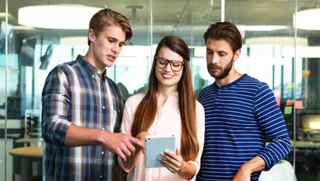 Executives-discussing-over-digital-tablet-in-office