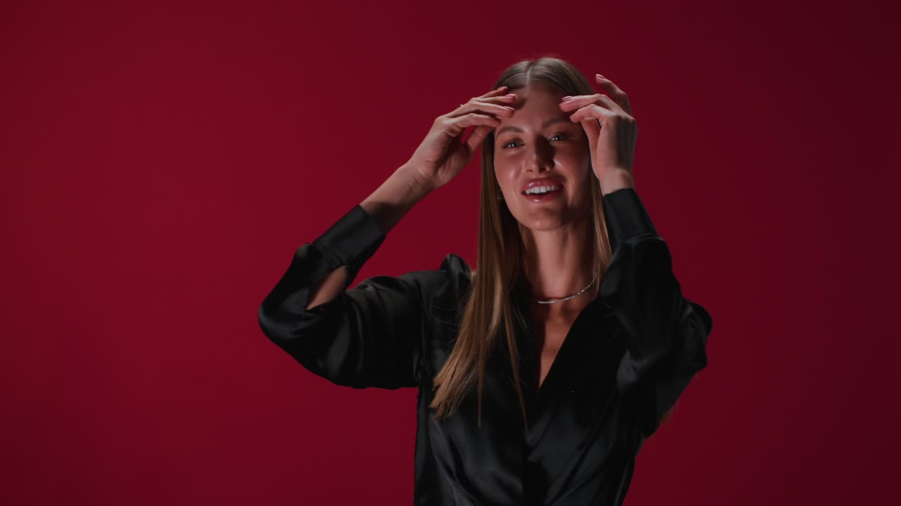 mujer con vestido de satén negro contra un fondo rojo