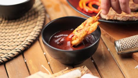 hombre sumergiendo pollo frito en salsa de barbacoa de cerca