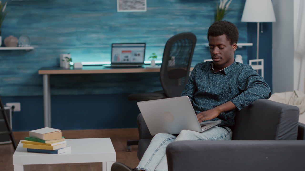 Overburdened overworking exhausted african american man suffering from sleep deprivation, falling asleep with laptop in front of him