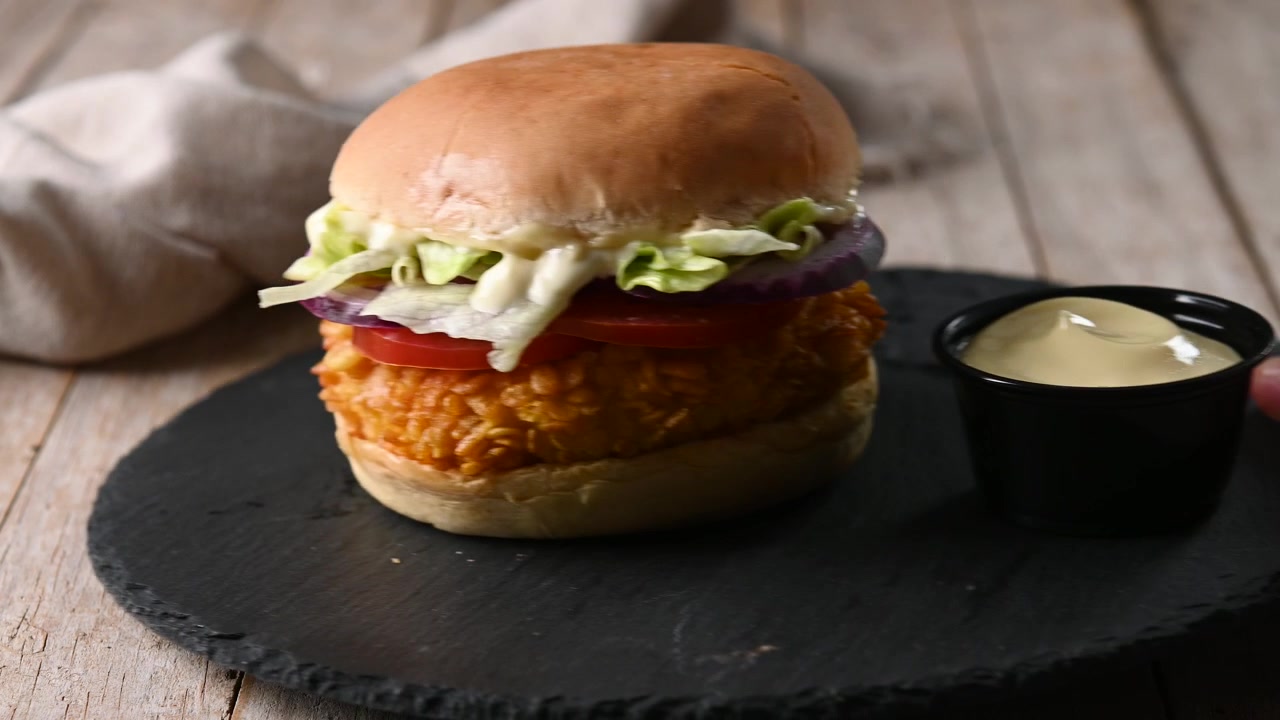 Hamburger di pollo croccante servito su tavolo di legno