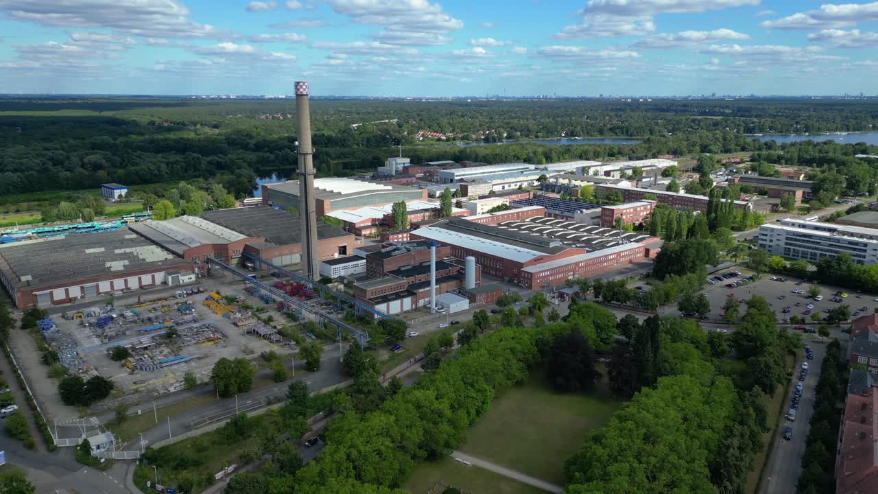 Hennigsdorf industrial area with modern offices, old factory buildings and chimneys under blue sky. Lovely aerial view flight speed ramp hyper motion time lapse fly push forward drone