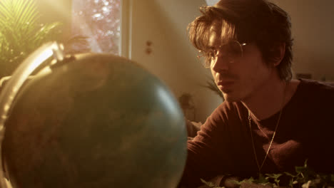 man thoughtfully looking at a globe