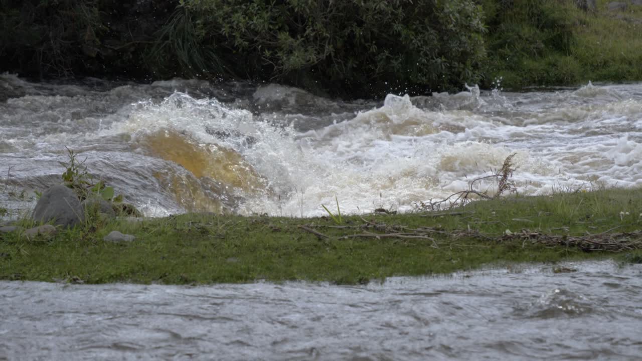 Slow motion video of wild, fast river stream forming a small waterfall, crashing and splashing
