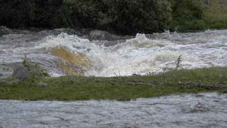 Video-En-Cámara-Lenta-De-Un-Río-Salvaje-Y-Rápido-Que-Forma-Una-Pequeña-Cascada,-Chocando-Y-Salpicando