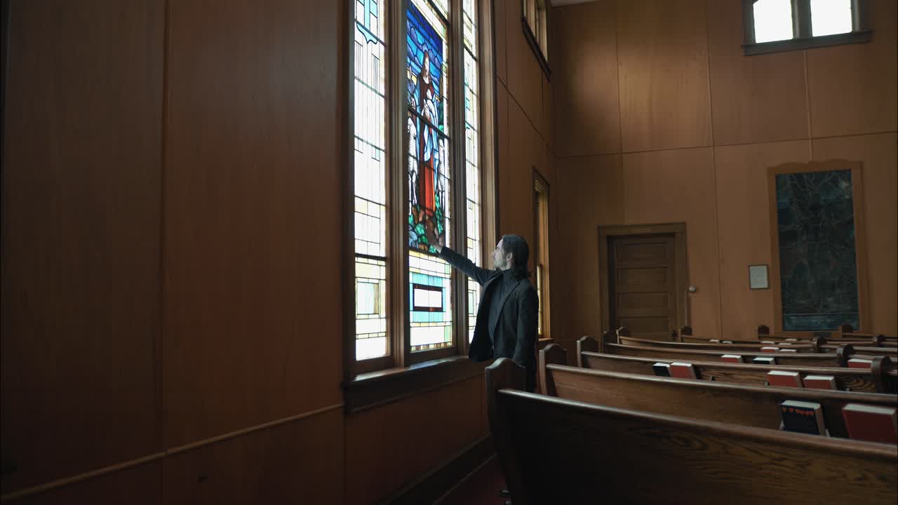 Spiritual man reaching out to touch a stained-glass church window. The shot captures intimacy, faith, and reflection, highlighting the vivid colors and sacred atmosphere