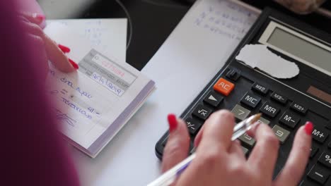 close up and pan of female accountant using calculator to calculate sales receipts