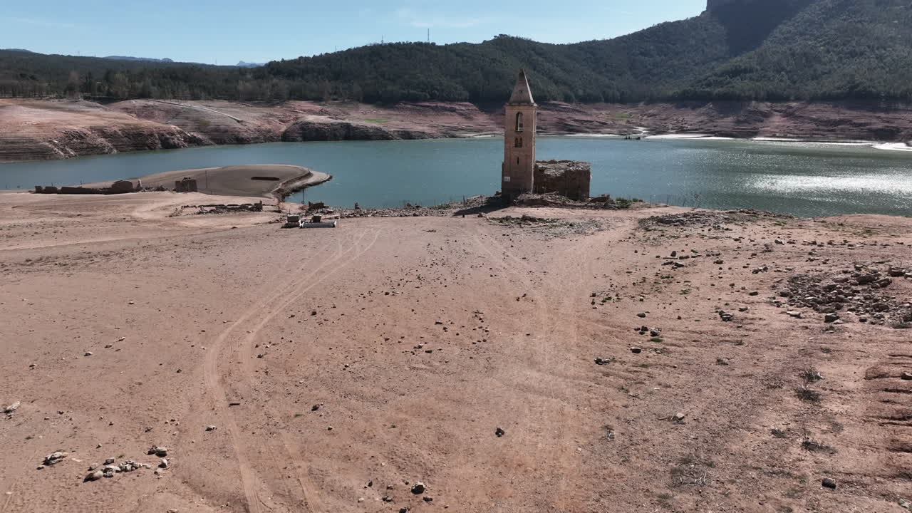 hombre caminando hacia la iglesia histórica resucitada en el embalse de sau, sequía