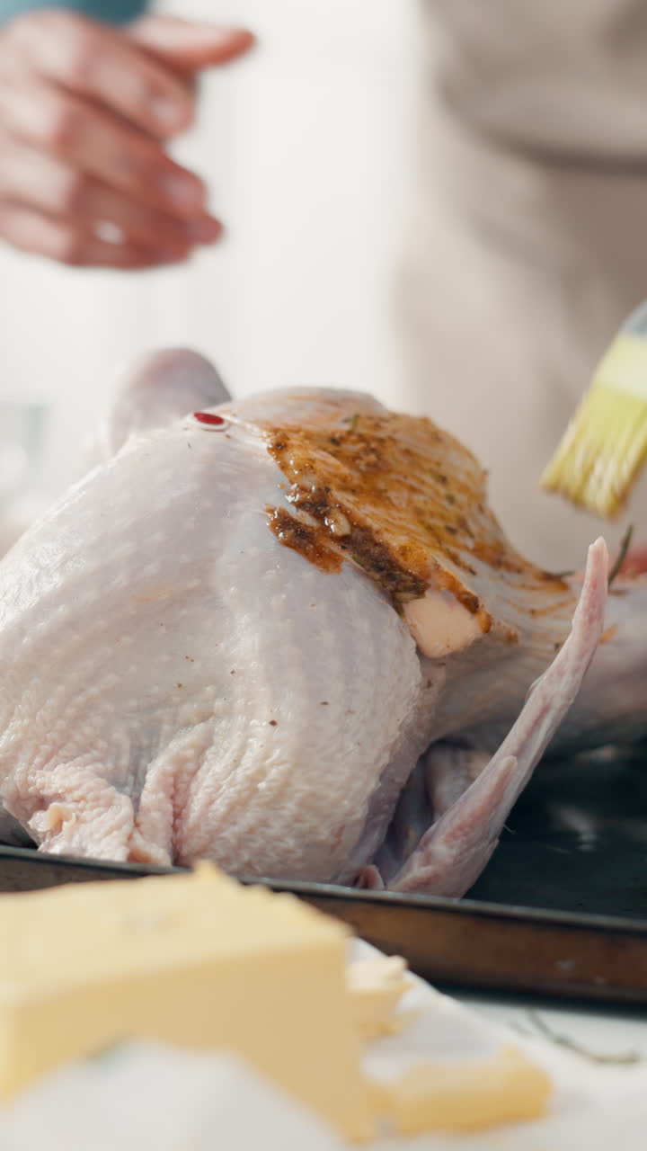 Persona che spennella la marinatura su un tacchino crudo per arrostirlo