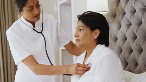 female doctor examining mature woman with stethoscope in bedroom 4k