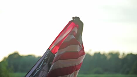 slow motion shot of woman lifting american flag into sky at golden sunset