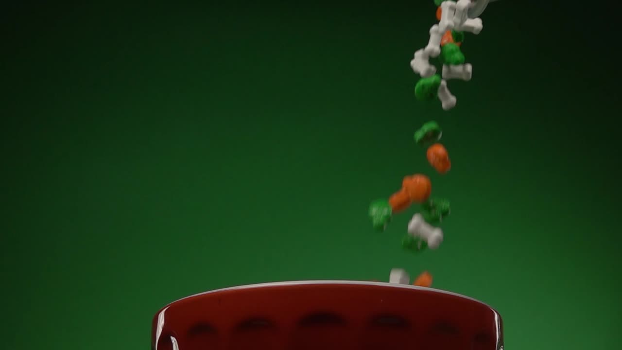 Skulls and bones shaped candy falling on a plate from above