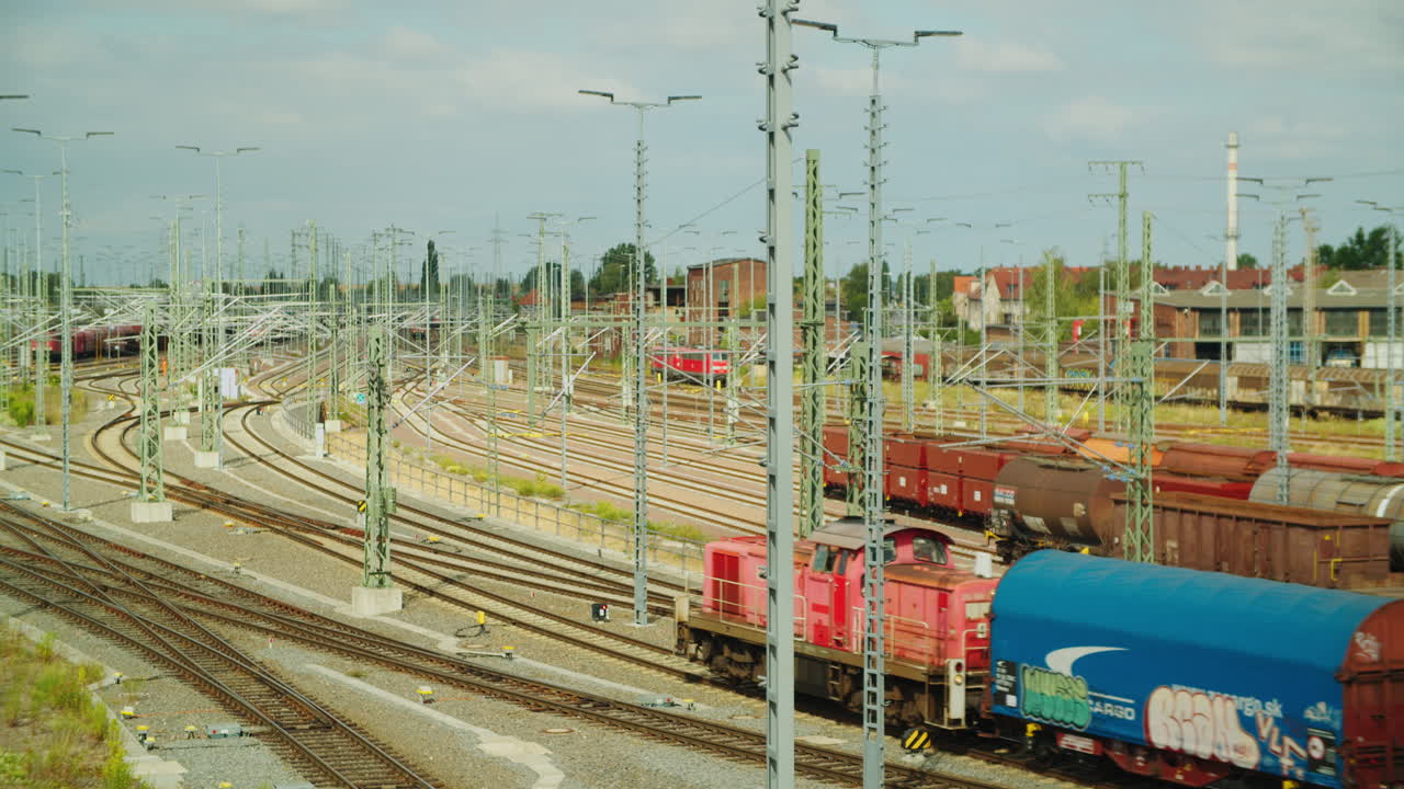 red locomotive with two freight cars in rail yard