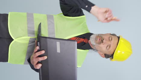 Vertical-video-of-Old-engineer-working-on-project-on-laptop.