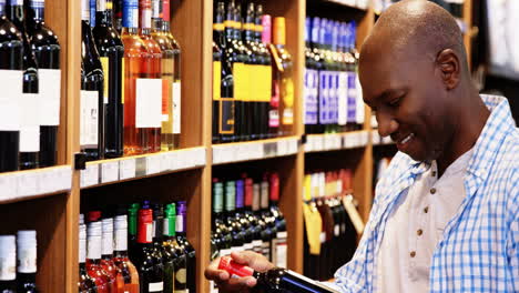 man looking at wine bottle in grocery section