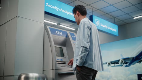 man using atm in airport