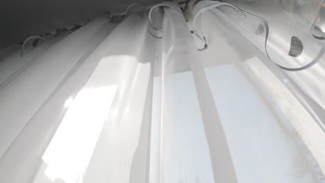 transparent white curtain tulle moves from wind from an open window