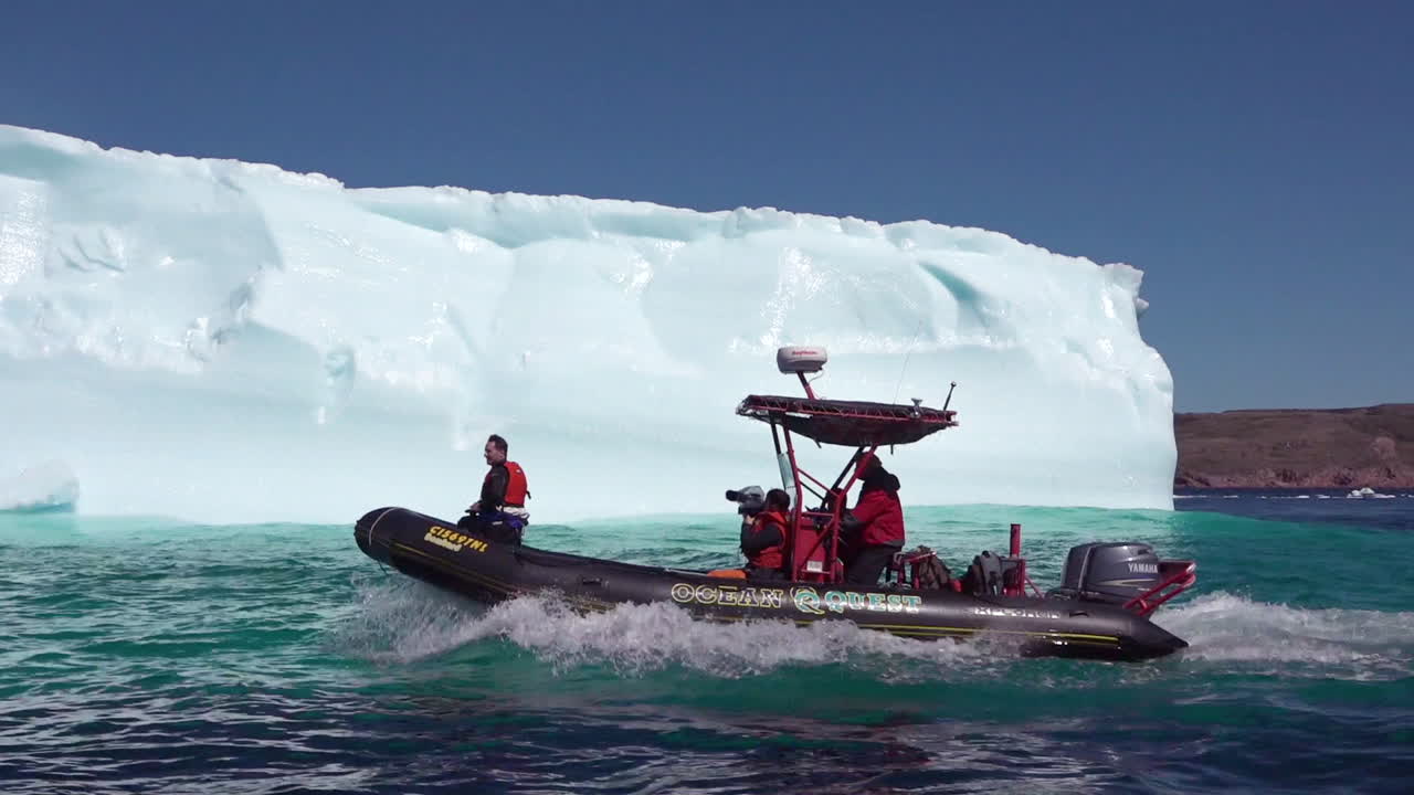 조디악 보트의 연구원이 북극 1에서 거대한 빙산을 통과합니다.
