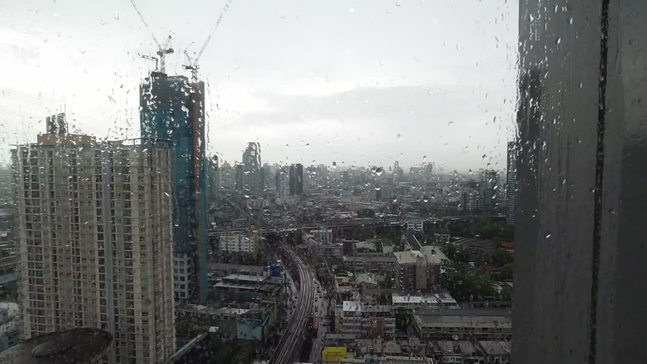la lluvia cae por la ventana. vista aérea. la lluvia fuera de la ventana de la sala de estar en la temporada de lluvias en bangkok, tailandia. la ventana exterior está borrosa por la lluvia del edificio de la ciudad y la carretera y el cielo.